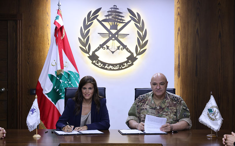 Dr Josette Najjar et Général Joseph Aoun are sitting next to each other, looking right into the camera while signing the agreement