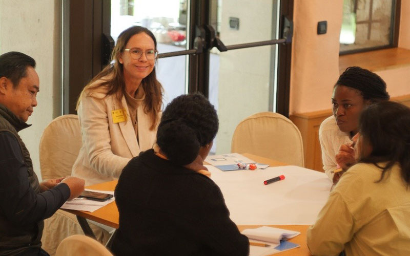 Participants in discussion sitting around a table during the 13th Advanced Course on Diagnostics in 2024.